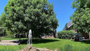 A garden with a fountain, trees, and a small structure with a striped awning. - 2-room apartment 22 (H) - Lancken-Granitz apartment complex (Lancken-Granitz)