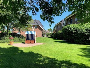 A well-maintained lawn with a wooden deck chair and a potted plant.