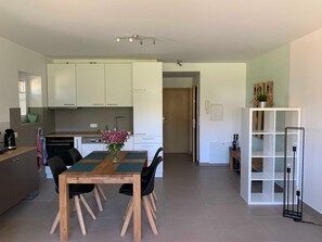 Une cuisine moderne avec des meubles blancs, une table à manger avec des chaises et un petit coin repas.