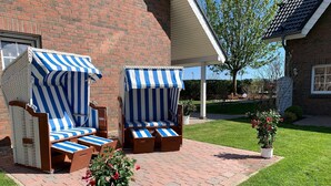A patio with two striped lounge chairs and a potted plant. - 3-room maisonette apartment 13 (AF) - Lancken-Granitz apartment complex (Lancken-Granitz)