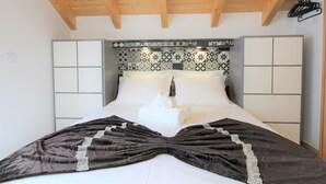 A bedroom with a wooden ceiling, a patterned headboard, a large bed with white linens, and a dark brown bedspread. - Estúdio-suite com Varanda a 2 Minutos a pé da Praia de Peniche (Peniche)