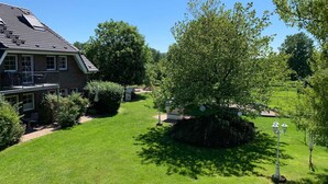 A house with a balcony, a well-maintained lawn, and a large tree in the yard.