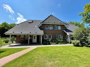 Une maison à deux étages, avec un toit en tuiles, une façade en briques et un porche couvert.