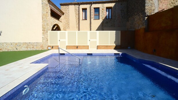 En swimmingpool med en steng bygning i baggrunden.