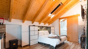 A bedroom with a wooden ceiling, a bed, a desk, and a small trash bin. - Estúdio-suite com Terraço a 2 Minutos a pé da Praia de Peniche (Peniche)