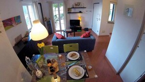 Een eetruimte met een tafel voor twee, een bank en een televisie op de achtergrond.