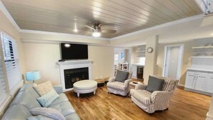 A living room with a fireplace, a sofa, striped armchairs, and a television.