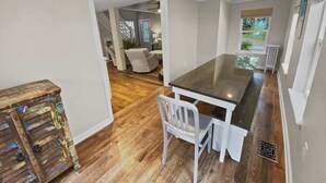 A modern kitchen with a dark countertop, white chairs, and a wooden floor.