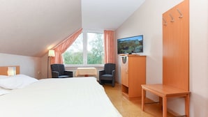 Une chambre d’hôtel comprenant un lit, un bureau, une chaise, un téléviseur et une armoire.