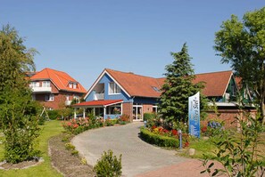 Ein Gebäude mit rotem Dach, blauer Fassade und einem gepflasterten Weg zum Eingang.