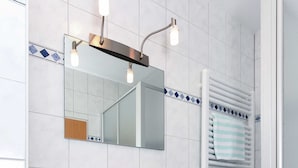 Une salle de bain avec un lavabo blanc, un miroir et un porte-serviettes.