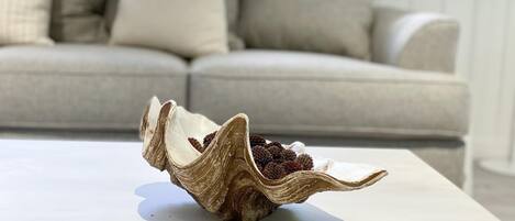 A seashell on a white table with a beige sofa in the background.