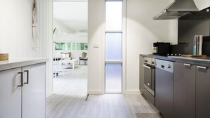 A modern kitchen with stainless steel appliances, a large window, and a view into a dining area.