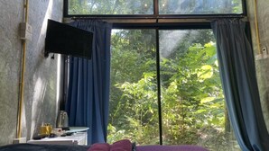 Una habitación con una cama, un televisor de pantalla plana en la pared y una ventana con cortinas.