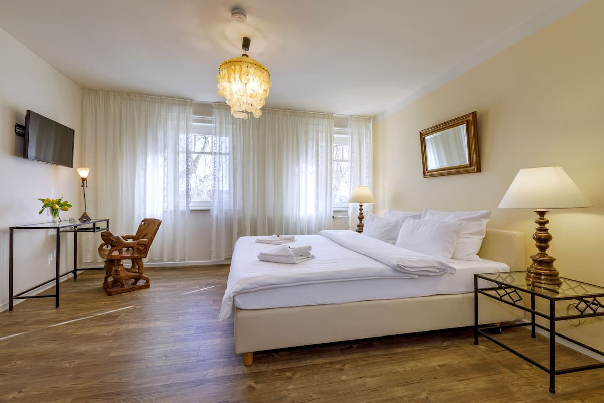 Een hotelkamer met een bed, een bureau, een stoel, een televisie en een kroonluchter.