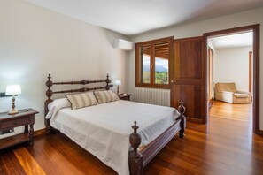 Un dormitorio con cama de madera, mesitas de noche, un radiador y vistas por una puerta.