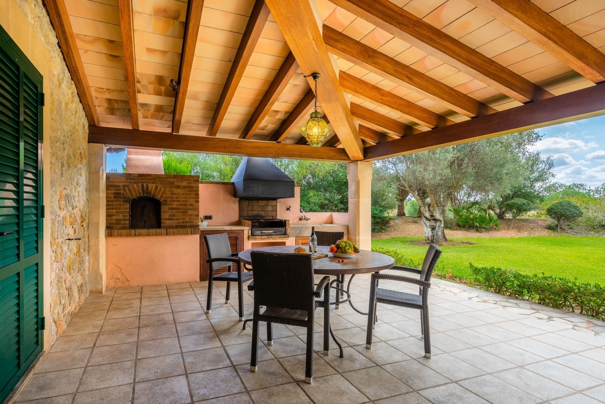 An outdoor patio with a brick oven, grill, and seating area.