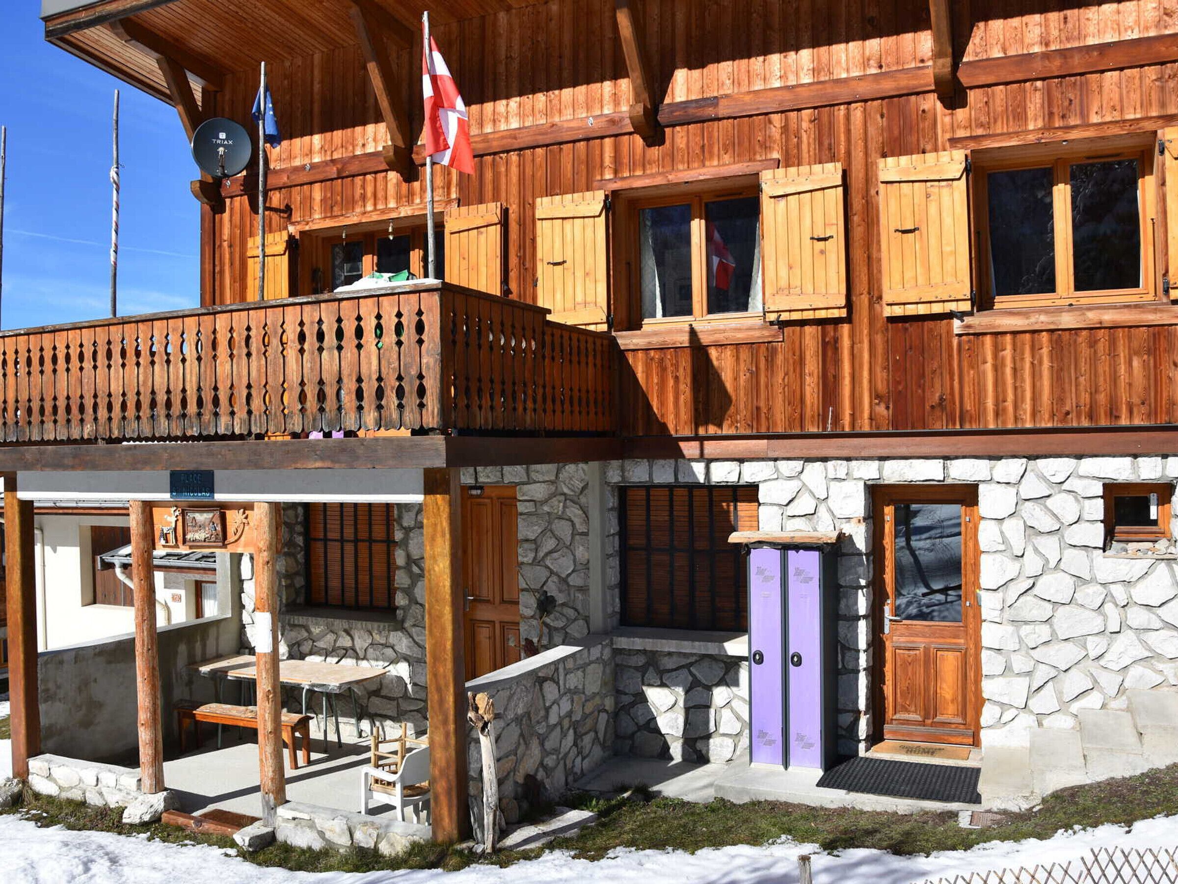 Un chalet en bois avec une façade en pierre, un balcon et un coin repas.