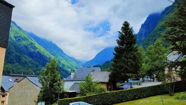 A residential area with houses, a car, and mountains in the background.