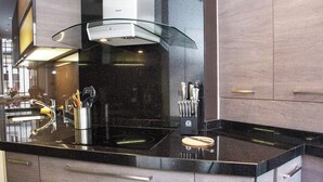A modern kitchen with a black countertop, stainless steel appliances, and wooden cabinets. - Enjoy Eiffel Tower Sparkle in Grand Style! (Paris)