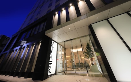 The exterior of the Richmond Hotel with a modern facade, large glass entrance, and a visible seating area outside.