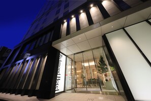 Exterior del hotel Richmond, con una fachada moderna, un amplio acceso de vidrio y un área de estar visible al aire libre.