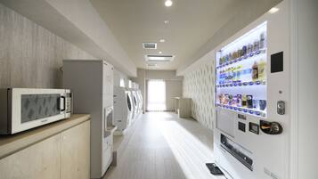 A hotel corridor with a microwave, washing machines, and a vending machine.