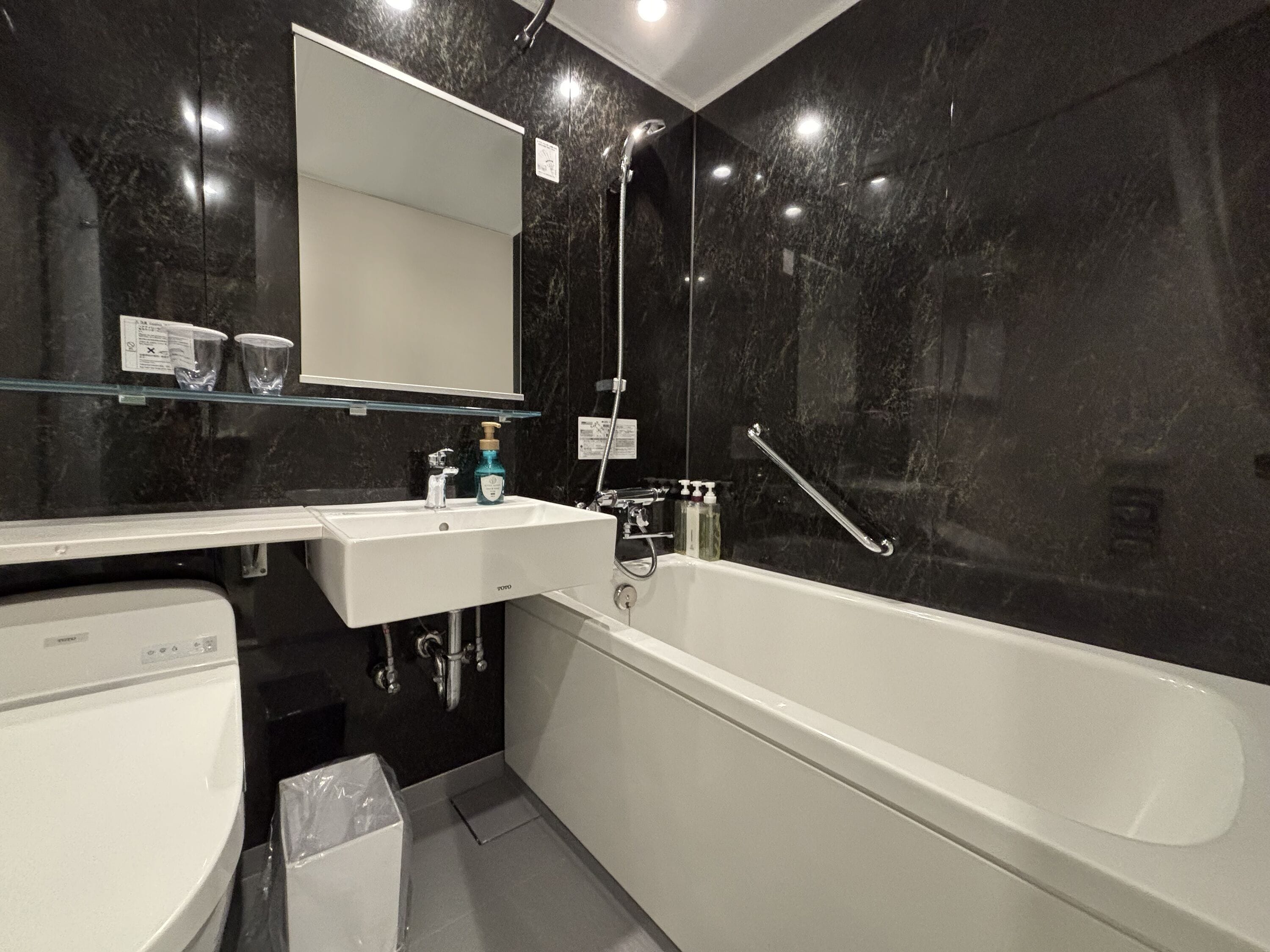 Un baño moderno con un lavamanos, espejo y bañera blancos.
