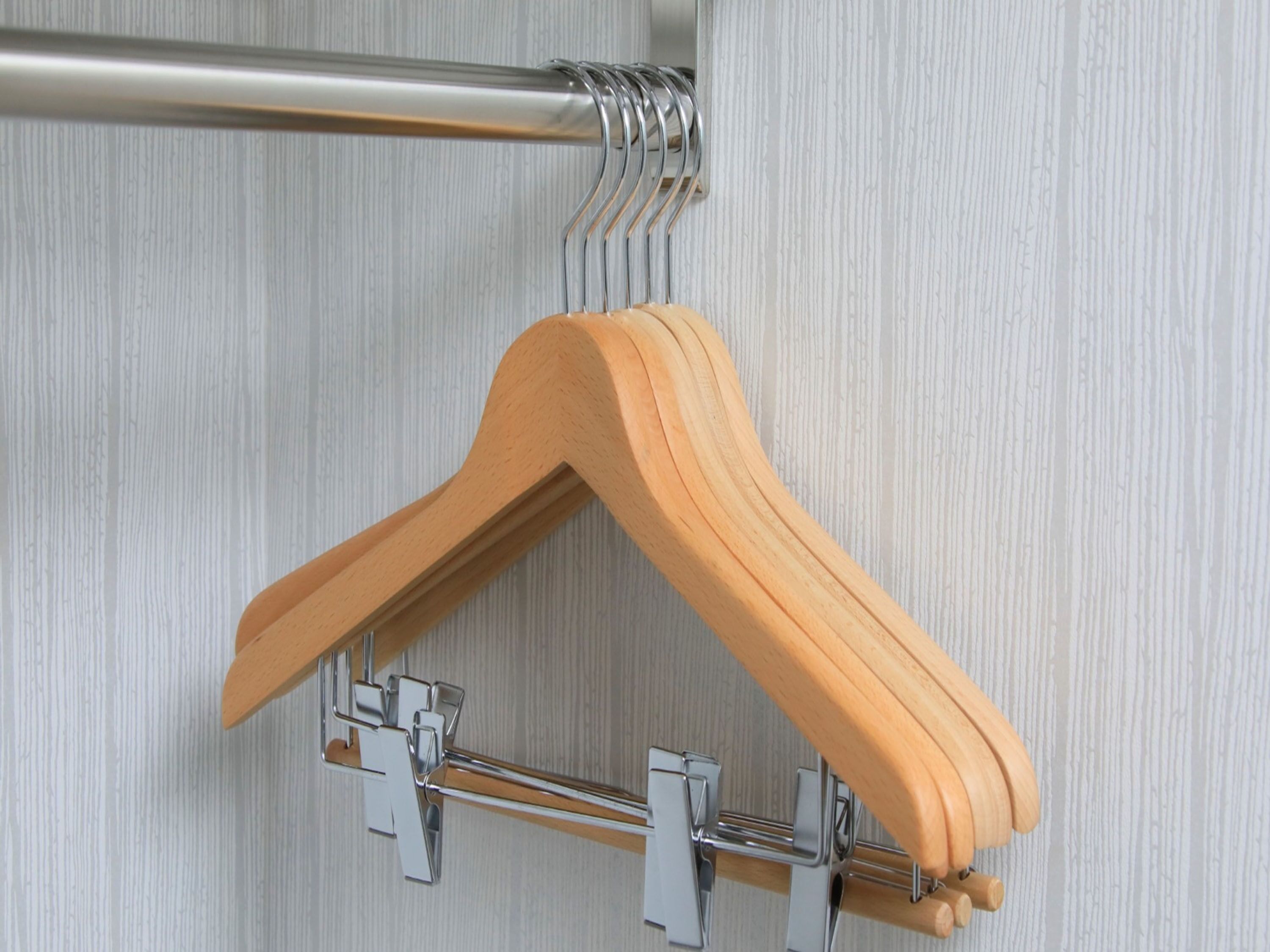 A wooden hanger on a metal rack against a textured wall.