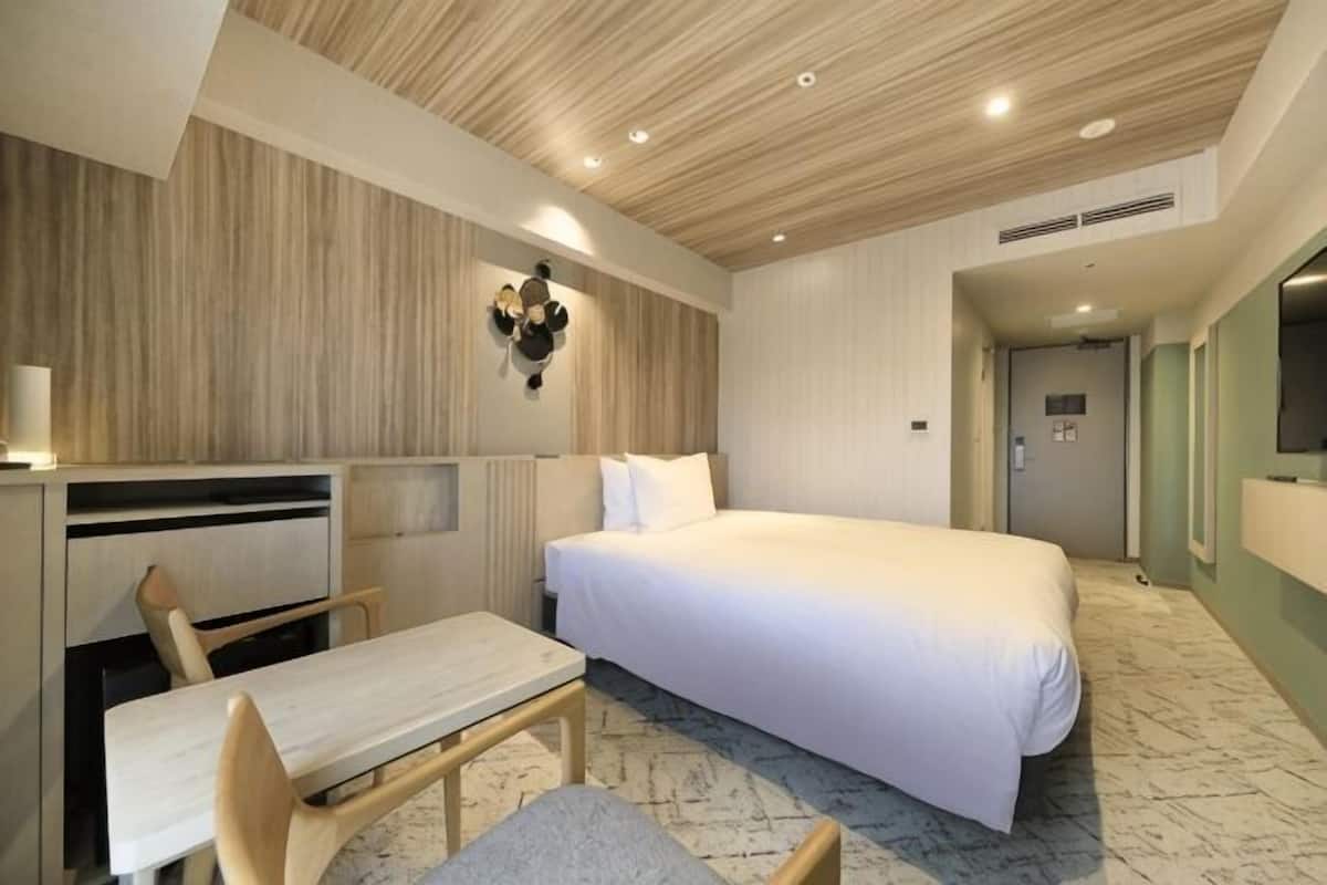 Une chambre d’hôtel avec un lit, un bureau et une chaise.