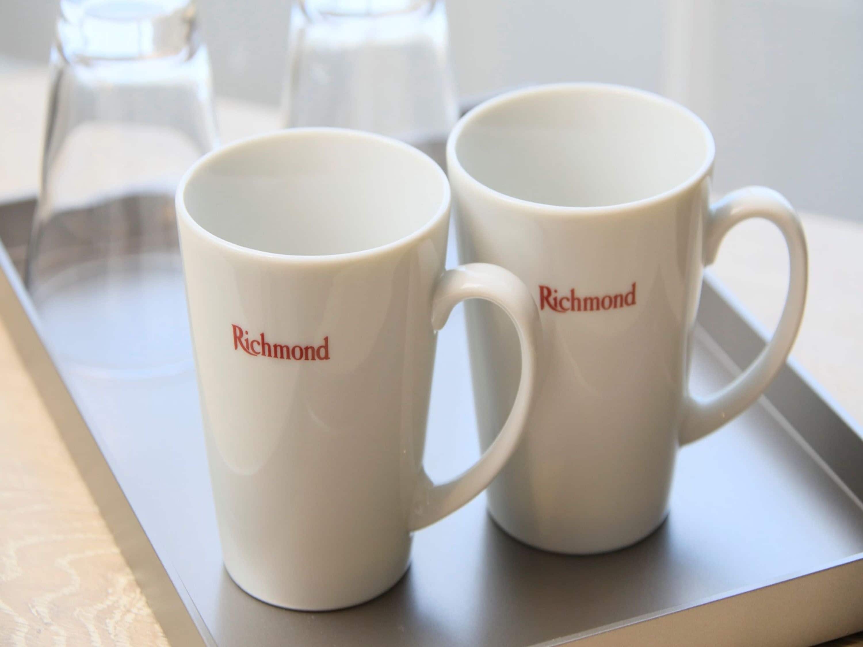 Dos tazas blancas con la palabra "Richmond" escrita sobre ellas, sobre una bandeja.
