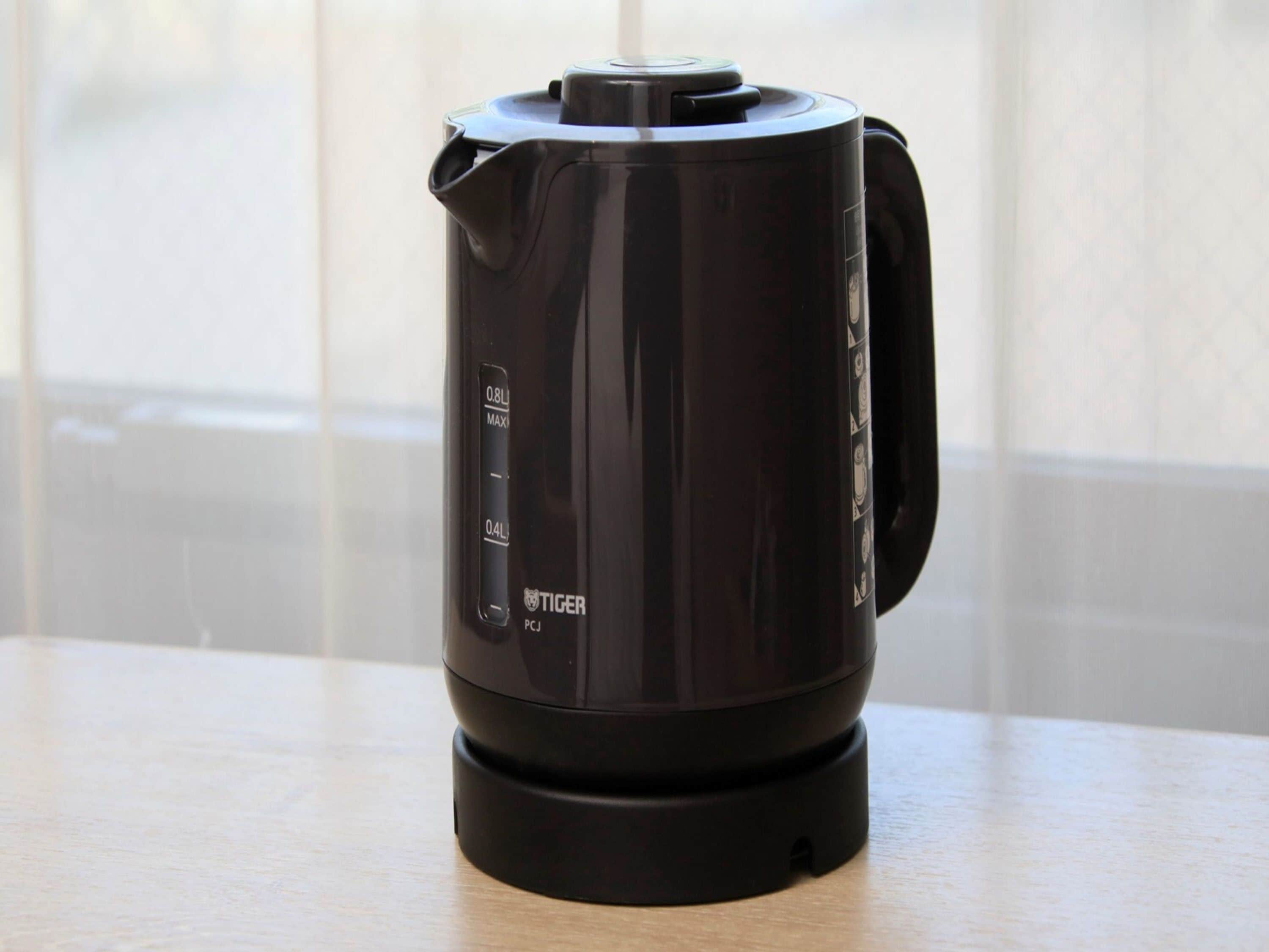 A black electric kettle with a digital display and a lid on a wooden table.