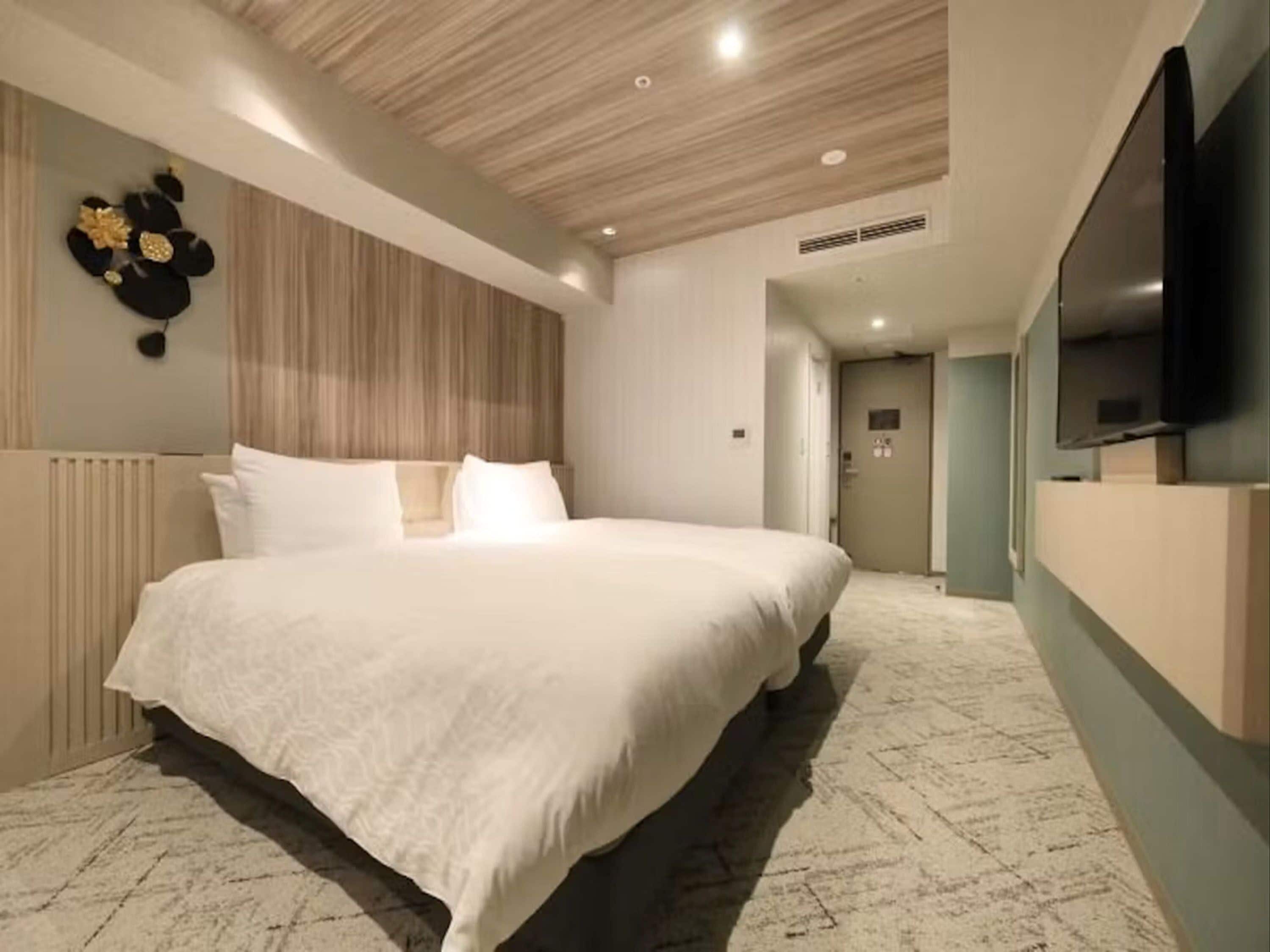 Habitación de hotel moderna con una cama grande, televisión de pantalla plana y un elemento decorativo en la pared.