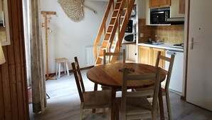 Cozinha com armários de madeira, micro-ondas e mesa de jantar de madeira com cadeiras.