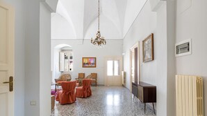 A spacious hallway with a high ceiling, a chandelier, and a radiator. - Antica Dimora Stasi by BarbarHouse (Acquarica del Capo)