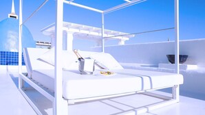 A white sun lounger with a bottle of champagne and a plate of food, set against a clear blue sky. - Royal Villa 2 people Alegria (La Oliva)