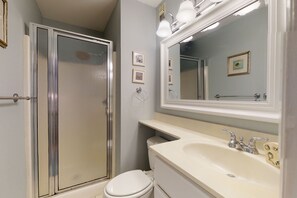 Bathroom features a shower enclosure, toilet, and sink with a mirror.