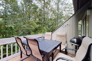Enjoy al fresco dining with a view of the surrounding woods from this outdoor deck, featuring a dining table and chairs.