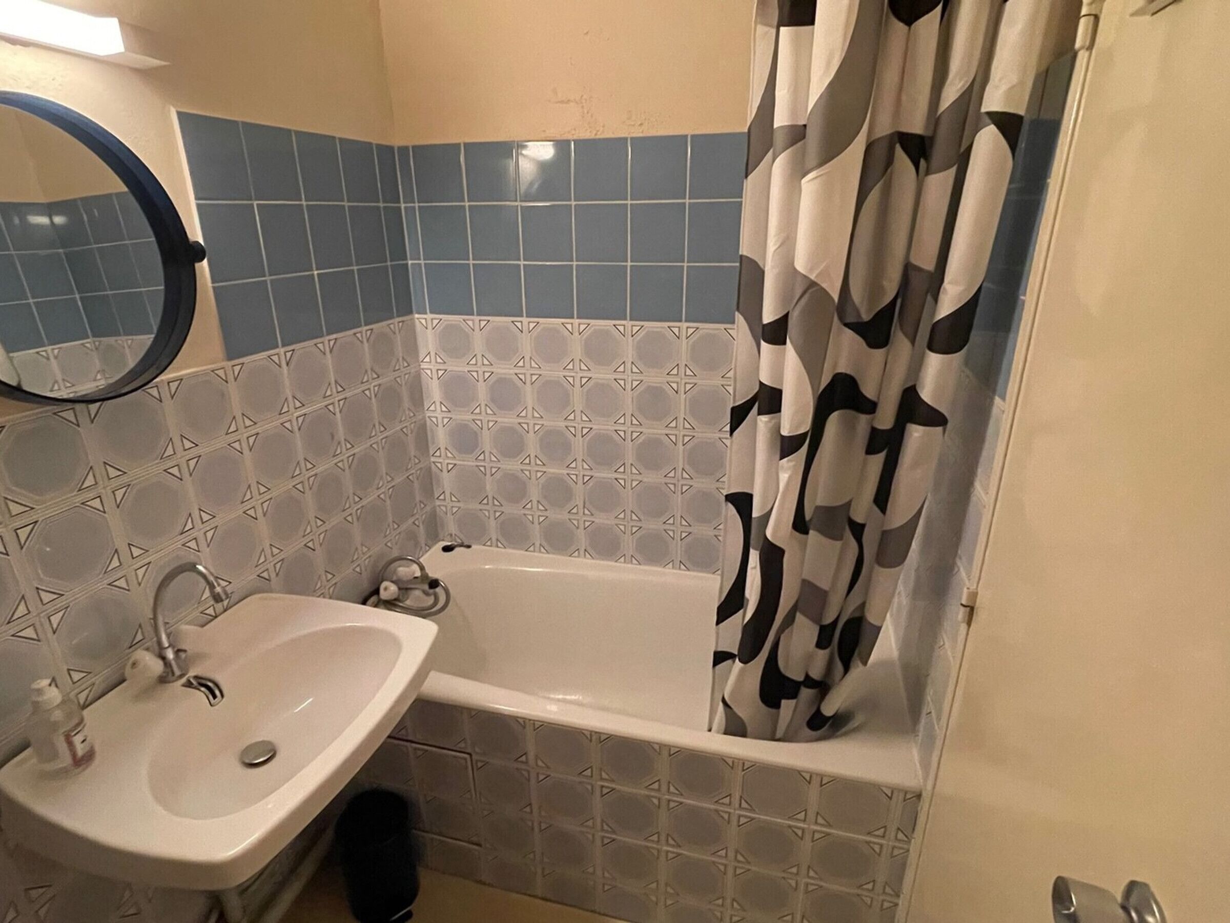 A bathroom with a sink, mirror, and bathtub.