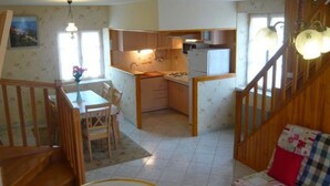 A compact kitchen with wooden cabinets, a dining table, and a staircase leading to a loft bedroom.
