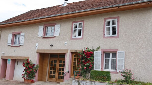 A two-story building with a tiled roof, wooden doors, and shutters.