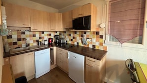 A compact kitchen with wooden cabinets, a microwave, a toaster, and a dishwasher. - 2-Bedroom Cabin Apartment with Parking, Lake View (Les Angles)