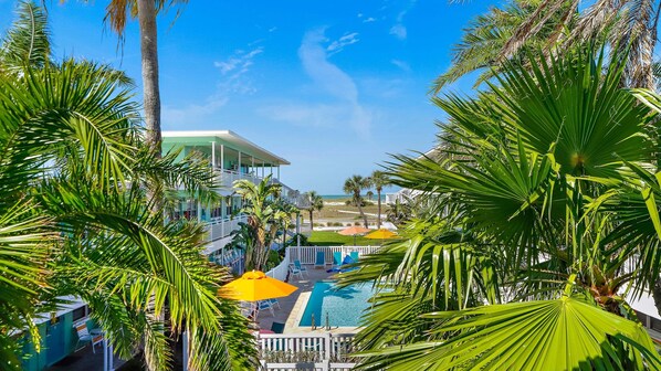 A resort with a pool, palm trees, and a view of the beach.