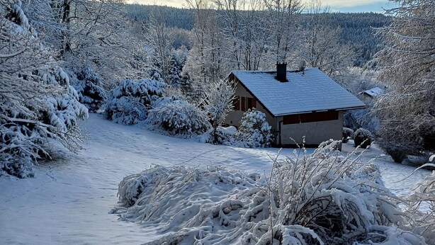 Schneebedeckte Landschaft mit einem kleinen Haus und einem Weg dorthin.