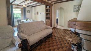A cozy living room with a checkered floor, a sofa, and a wooden cabinet. - Charming Mountain View Cottage Near Gérardmer: Spacious, Cozy, Garden, Parking, Ideal for Hikes (Jussarupt)