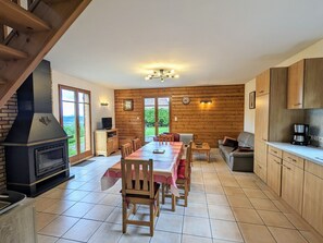 Interior acogedor de una cabaña con comedor, cocina y chimenea.