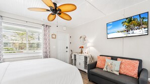 Une chambre à coucher avec un lit, un canapé, une télévision et un ventilateur de plafond.