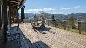 A wooden deck with a table and chairs, overlooking a mountainous landscape. - Comfortable chalet with terrace and wood stove, pets allowed (Le Tholy)