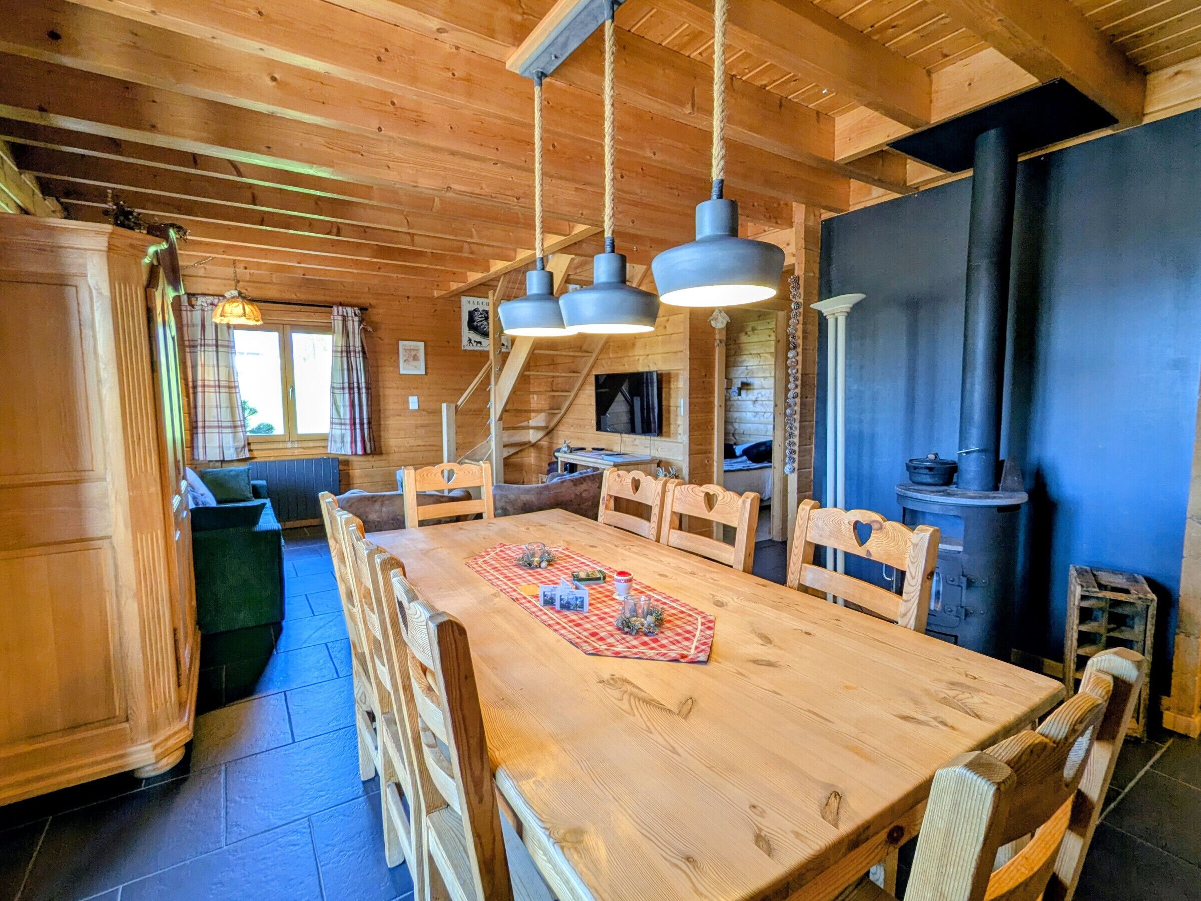Ein Holzinnenraum mit Esstisch, Stühlen, einer Treppe und einem Kamin.