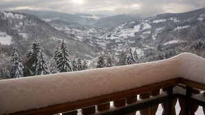 A snowy mountain landscape with a wooden balcony railing.